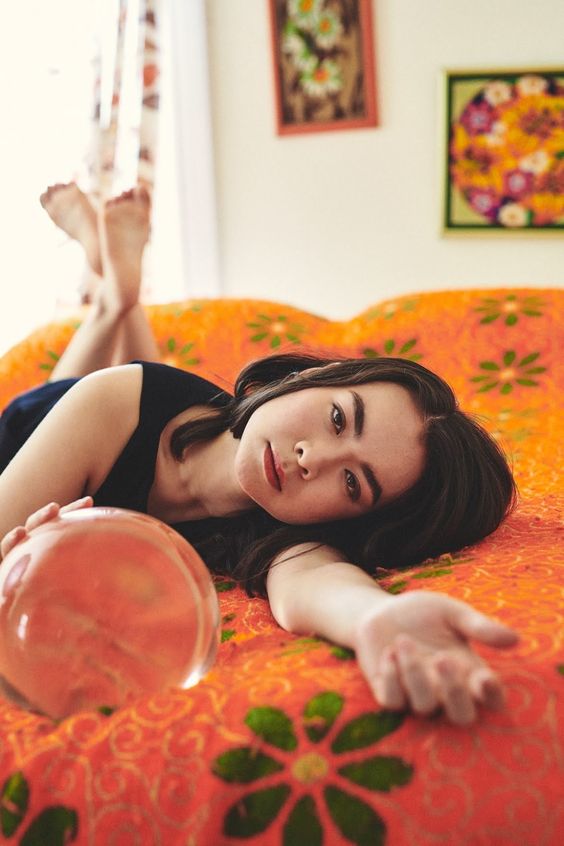 Mitski | Mitski laying on a orange floral print bed | Girlfriend is Better